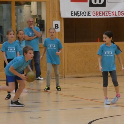 Ein Schüler mit dem Ball in der Hand kurz vor dem Abwurf, im Hintergrund 4 Kinder und der Lehrer