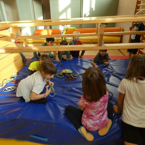 Turnsaal - Kinder sitzen auf einem Weichboden - dem Tal des Todes -  mit vielen Gummischlangen