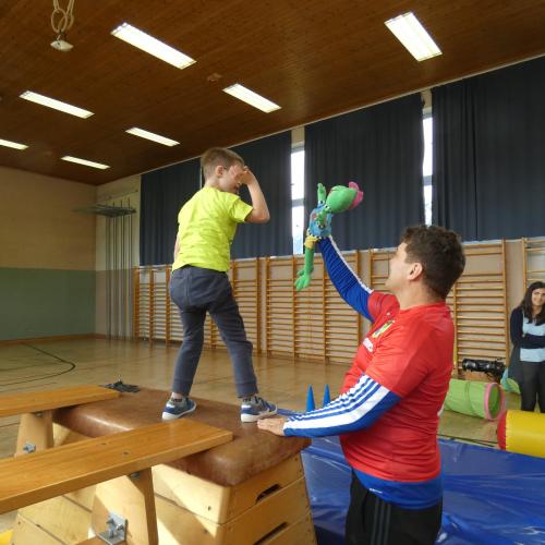 Turnsaal - ein Kind beim Abklatschen mit dem Frosch "Hopsi Hopper"