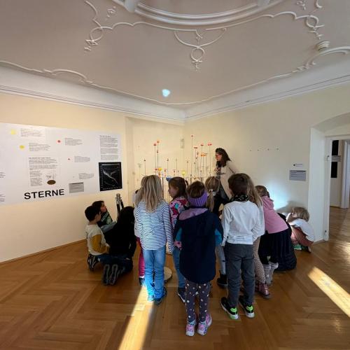 Kinder stehen im Museum vor einem Modell des Sonnensystems