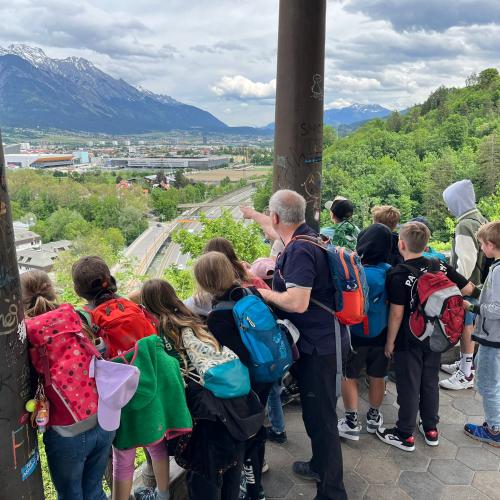Kinder stehen am Bergisel und schauen auf die Stadt Innsbruck Richtung Osten