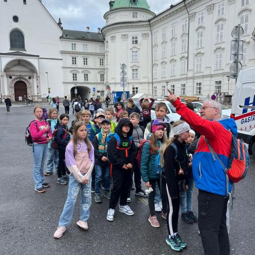 Lehrer erklärt der Kindergruppe etwas vor der Hofburg