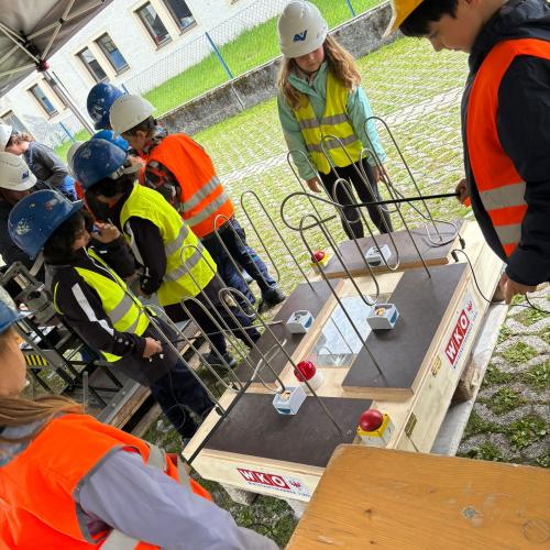 Einige Kinder mit Schutzkleidung (Warnweste und Helm) bei einm Versuch mit Strom