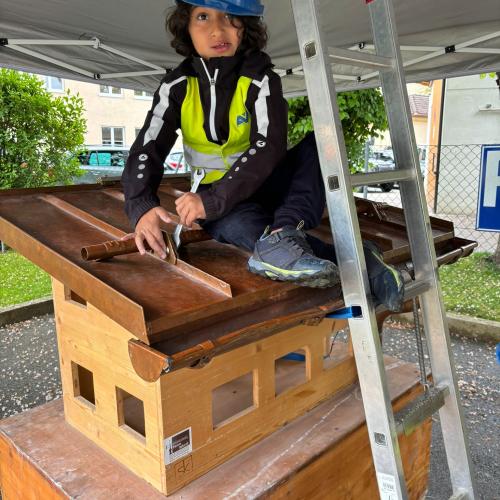 Ein Kind am Modell eines Daches bei Spenglerarbeiten