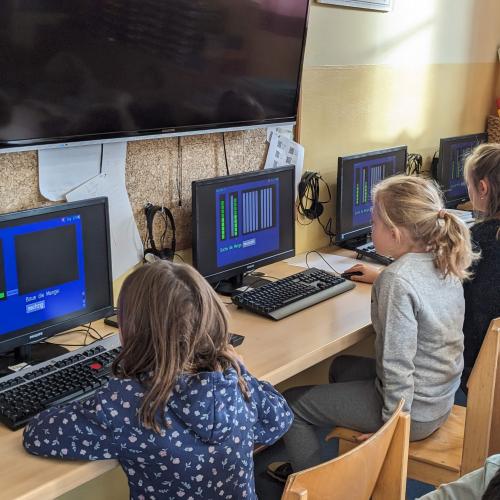 4 Kinder sitzen an den Computerarbeitsplätzen und bauen Zahlen mit Zehnern und Einern