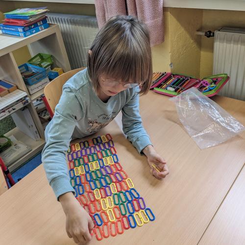 Ein Mädchen hat 100 bunte Kettenglieder in Reihen zu 10 aufgelegt