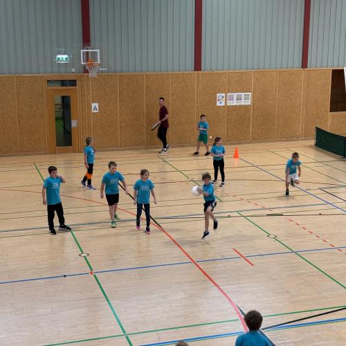 Sporthalle Reutte - Blick von der Tribüne auf ein Spielfeld wo 8 gegen 8 Kinder gegeneinander Völkerball spielen