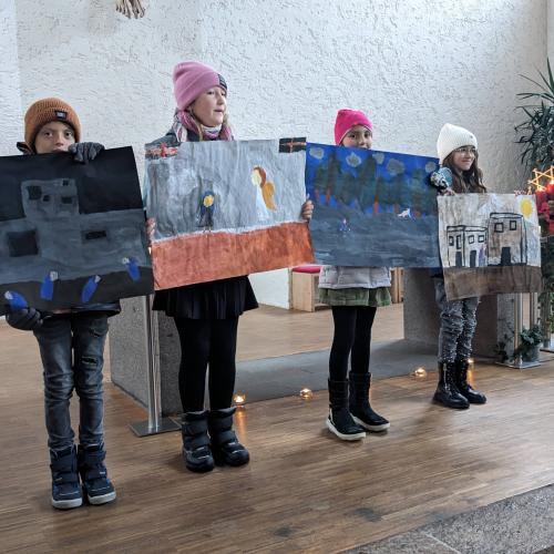 4 Kinder stehen in der Kirche und halten ihre großen Zeichnungen A2 zur Geschichte vor sich.