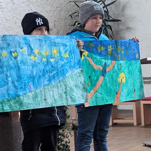 2 Kinder stehen mit ihren Zeichnungen zur Geschichte am ALtar