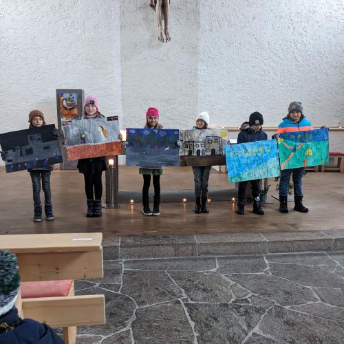 6 Kinder, die die Geschichte illustriert haben, stehen mit ihren großen Bildern vorne in der Kirche und zeigen sie.