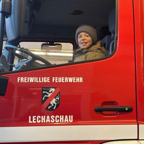 Ein Junge sitzt im Feuerwehrauto und schaut aus dem Fenster