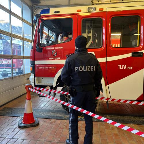 Ein Feuerwehrauto steht in der Garage in Lechaschau, davor steht ein Polizist