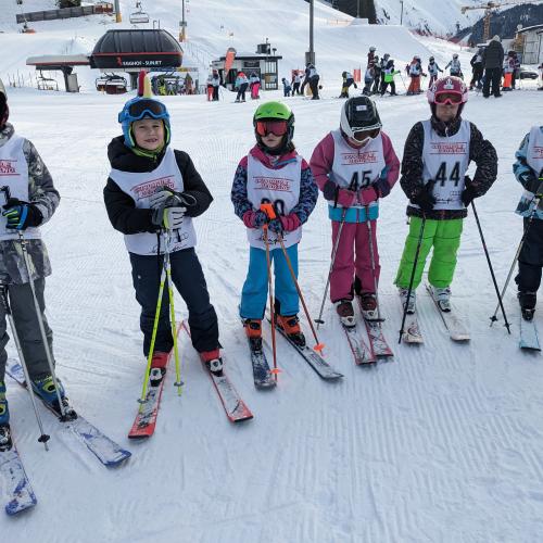 6 Kinder warten mit bereits angezogenen Startnummern auf das Schirennen