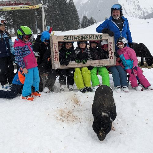 Eine Gruppe von Kindern im Schigebiet Berwang beim "Schweinekino" mit Schwein Esa und Schilehrer Christianein 