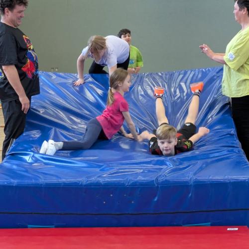 3Kinder klettern / rutschen über einen Parcours aus blauen Weichböden