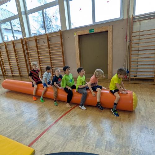 6 Buben hüpfen auf einer großen gelben aufblasbaren Gumminudel.