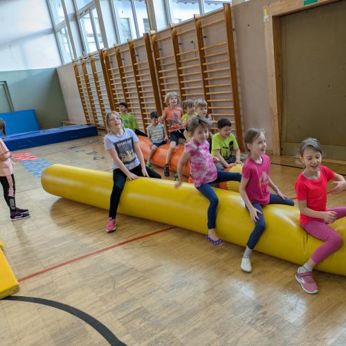 Einige Mädchen hüofen sitzend auf einer großen aufblasbaren Gumminudel.