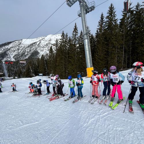 Eine Gruppe Kinder steht schon mit Startnummern in einer Schlange und wartet auf den Start des Schirennens