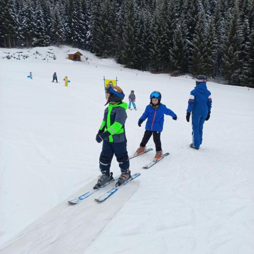 3 Kinder der Anfängergruppe fahren hintereinander im Kinderland der Schischule Berwang