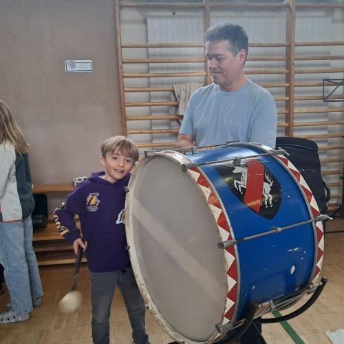 Ein kleiner Junge versucht sich an dergroßen Trommel, daeben steht ein Herr der MK