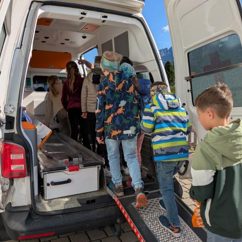 6 Kinder betreten von hinten über die Rampe das Rettungsauto und schauen drinnen alles an