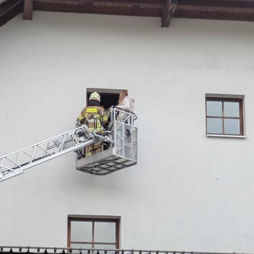 Der Bergekorb der Drehleiter vor dem Fenster im zweiten Stock. Im Korb siht man zwei Feuerwehrleute.