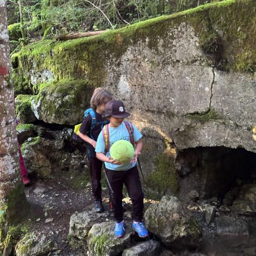 2 Kinder mit einem Fußball vor einem Felsen