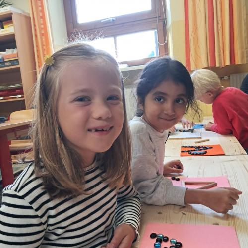 Zwei Mädchen legen mit Glassteinen Buchstaben