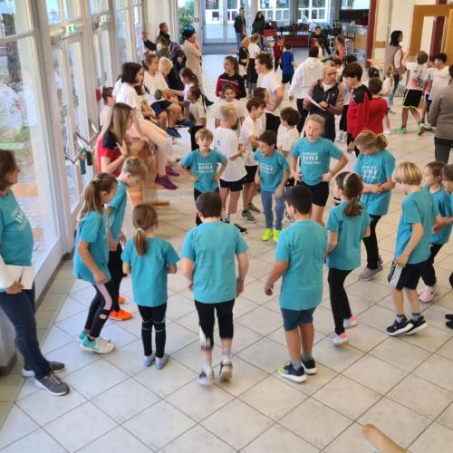 Die Kider der 3a Klasse stehen in der Eingangshalle und wärmen sich mit ihrem Betreuer auf.