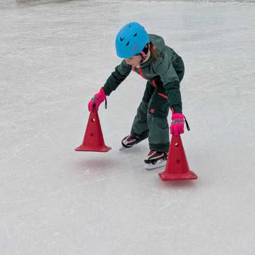 ein Kind stellt 2 Pylonen auf das EIs