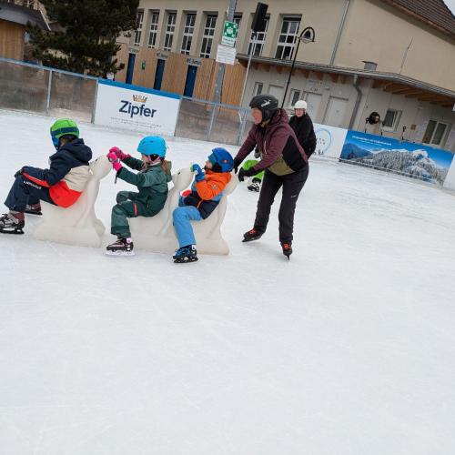 3 Kinder sitzen auf den "EIsbäen" , bilden eine Schlange und werden von einer Erwachsenen geschobenn
