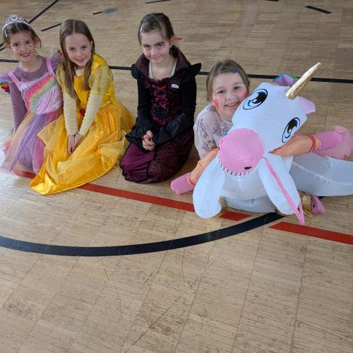 4 Kinder sitzen im Turnsaal am Boden verkleidet als Einhorn und Prinzessinnen