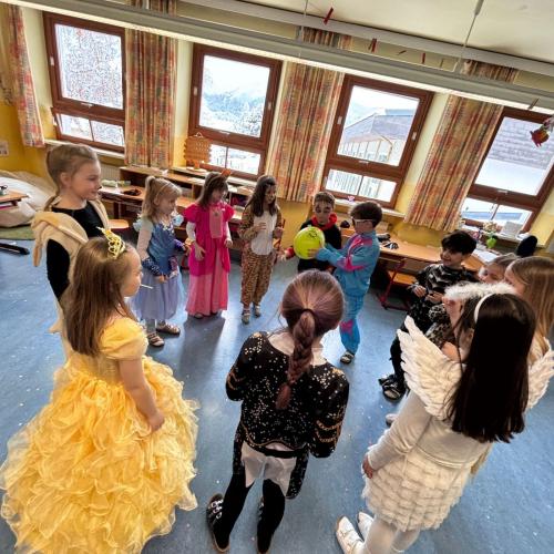 EIn Kreis verkleideter Kinder in einer Klasse - sie spielenein Spiel mit einem Luftballon