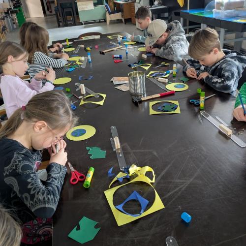 An einem großen Tisch im Werkhaus Reutte sitzn die Kinder und basteln einbewegliches Model von Sonne, Erde und Mond