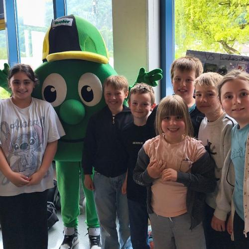 Eineige Kinder stehen zusammen mit Tiroly dem Maskottchen einer Versicherung