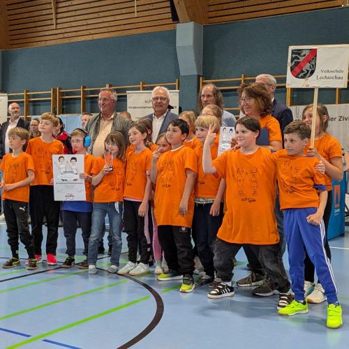 Siegerehrung - alle Kinder stehen mit dem Pokal und Urkunde für ein Foto zusammen mit der "Prominenz"