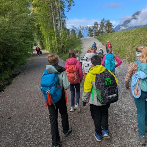 Die Kinder wandern mit ihren Rucksäcken am Weg zum Lechdamm