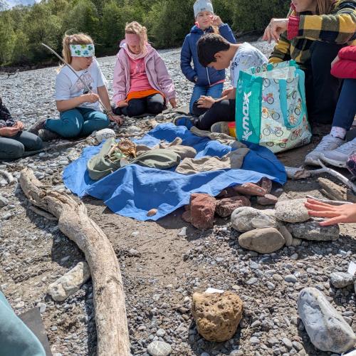 Die Kinder sitzen mit Sabine um die gesammelten und bestimmten Gesteine