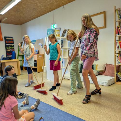 4 Kinder stehen mit Gartenbesen auf der Bühne und machen damit Musik