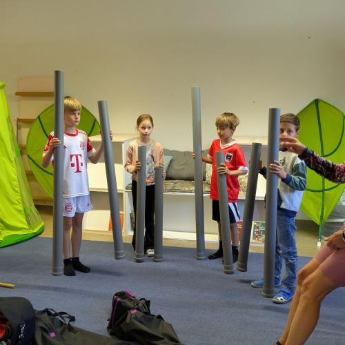 4 Kinder stehen im Halbkreis und jeder hat in jeder Hand lange Installationsrohre um damit Musik zu machen