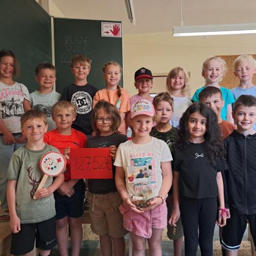 Klassenfoto der 1 Klasse im Klassenraum mit einm Schild über den Erlös des Eisverkaufs