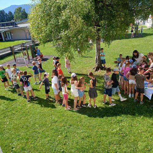 Blick von oben (aus einem Fenster der Schule) auf den Schulhof, wo die Kinder anstehen um ein Eis zu kaufen
