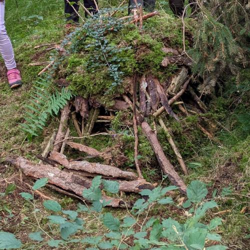 Man sieht ein aus Moos und kleine Zweigen und Rinde gebautes Mäusehäuschen