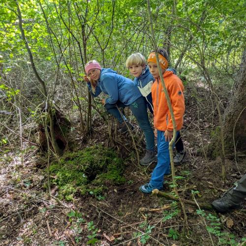 3 Kinder stehen vor ihrem in den Boden gebauten Mäusehöhle
