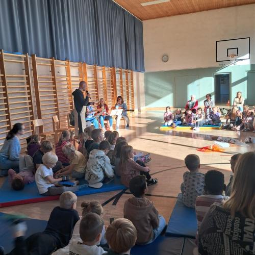 DIe Kinder sitzen im Tursaal auf Langbänken und MAtten bei der gemeinsamen Andacht