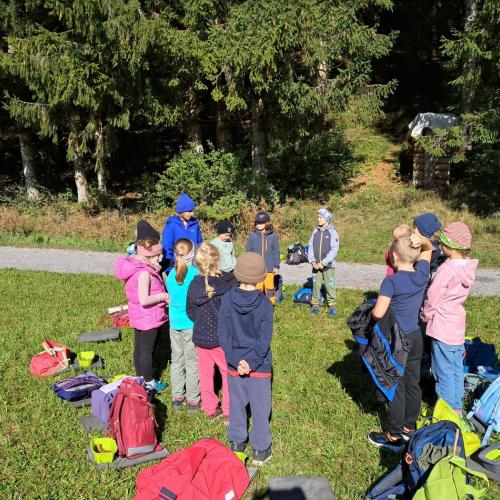 Waldrand - Kinder stehen im Kreis, hinter ihnen am Boden ihre Rucksäcke