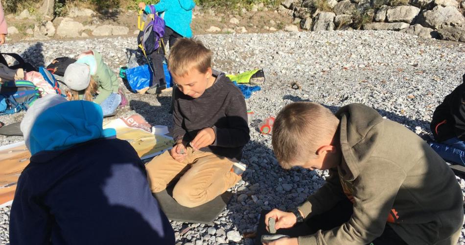3 Kinder sitzen am Boden und klopfen Steine