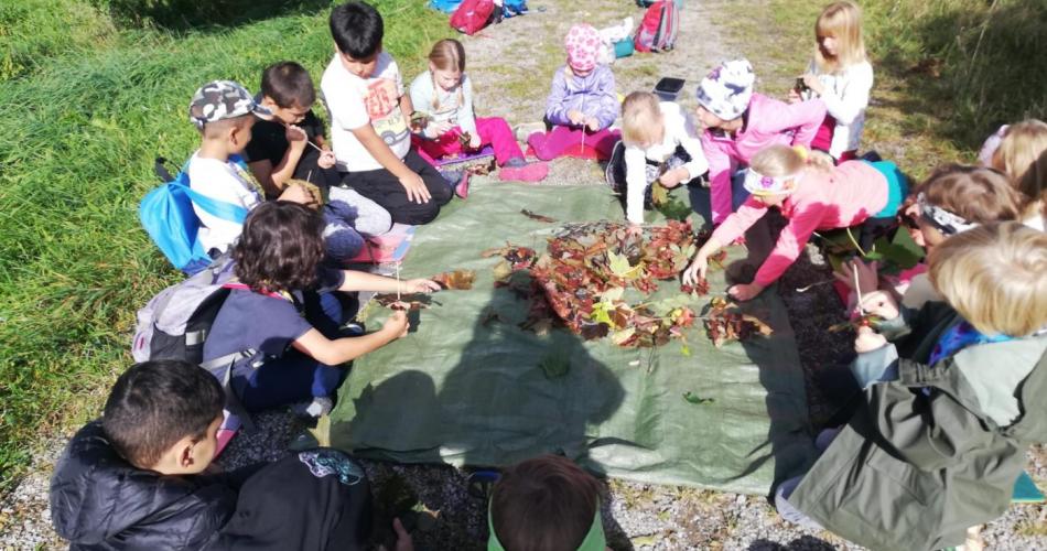 Kindergruppe sitzt im Kreis und bastelt mit Herbstblättern