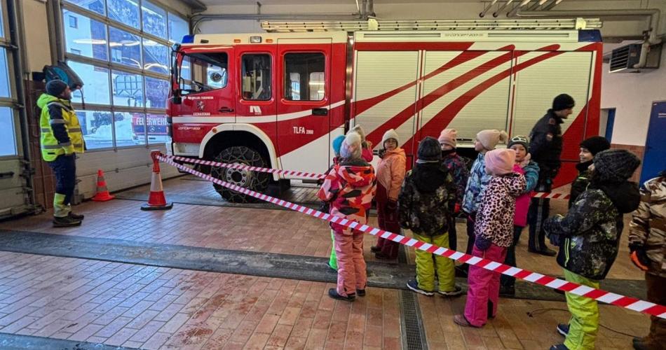 In der Garage der Freiwilligen Feuerwehr Lechaschau. ein eGruppe Kinder steht vor dem Feuerwehrauto