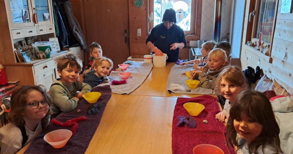 Am Bauernhof der Familie Wex sitzen die Kinder an einem langen Tisch und filzen ein kleines Schaf